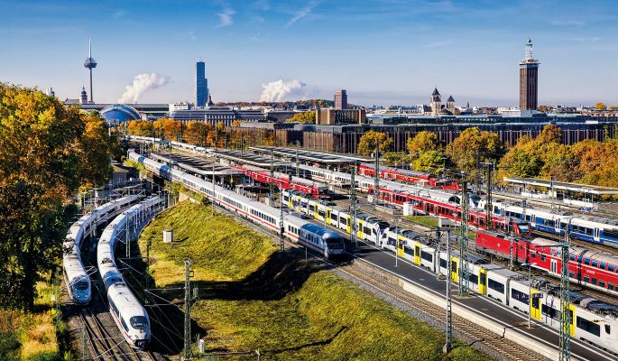 Gleise voller Züge mit dem Panorama Kölns im Hintergrund