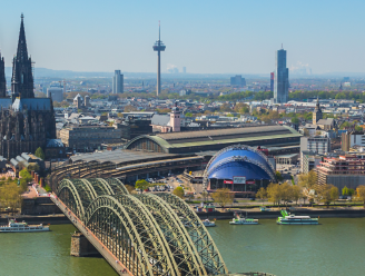 Ein Panoramabild von Köln. Im Vordergrund ist der Rhein mit der Hohenzollernbrücke. Im Hintergrund befindet sich der Dom. Rechts im Bild ist der Musicaldom Köln.