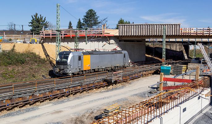 Ein Zug steht inmitten einer Baustelle auf Schienen.