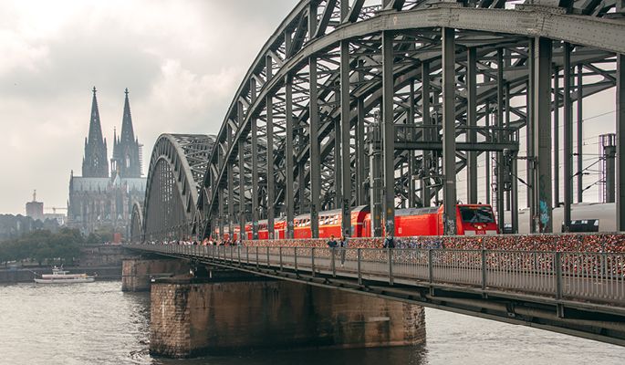 Ein Zug fährt über die Hohenzollernbrücke mit dem Kölner Hauptbahnhof im Hintergrund
