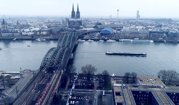 Flugaufnahme des Kölner Hauptbahnhofs mit der Hohenzollernbrücke und dem Rhein im Vordergrund.